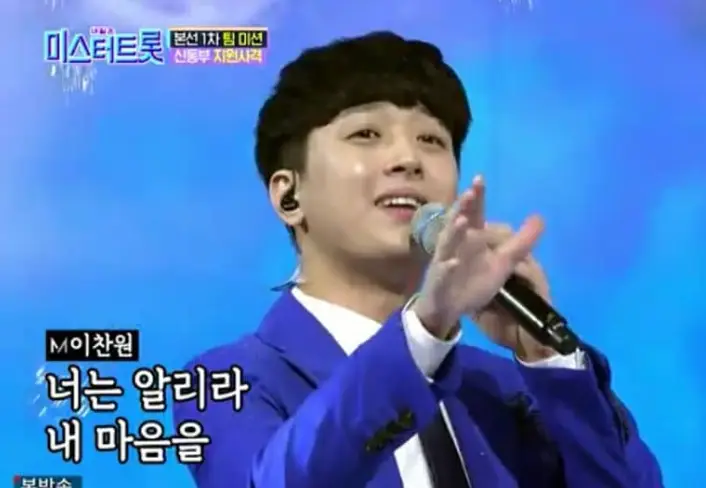 이찬원-파란 무대배경 파란 정정을 입고 완손으로 마이크를 든채 노래하는 이찬원