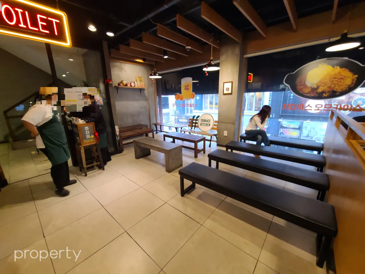 검은색기다란의자-나무의자가있는대리실-입구에직원2명이서있고-대기좌석에는여자한명이앉아서창밖을본다