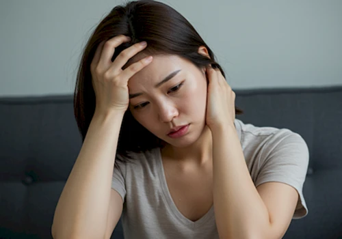 무리한 다이어트로 지쳐 보이며 두통을 느끼는 듯 머리를 감싸 쥔 한국 여성의 실사 이미지 *이미지 주제: 다이어트 부작용으로 인한 건강 악화와 스트레스