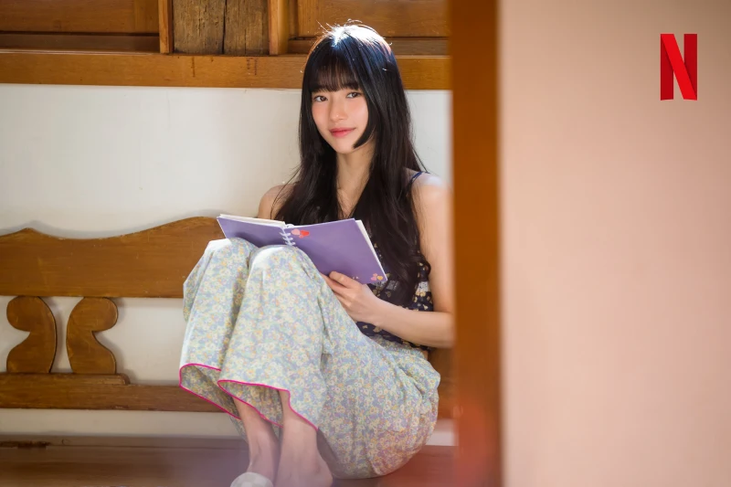 문틀에 앉아 노트를 펼치고 있는 드라마 이두나에 출연한 배우 수지