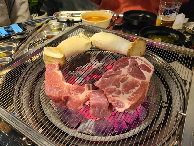 맛있게 구워지고있는 목살 두덩이와 새송이버섯 두개