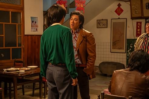 식당 안에서 가죽 재킷을 입은 남성이 초록색 스웨터를 입은 청년과 대화를 나누는 긴장된 분위기의 장면