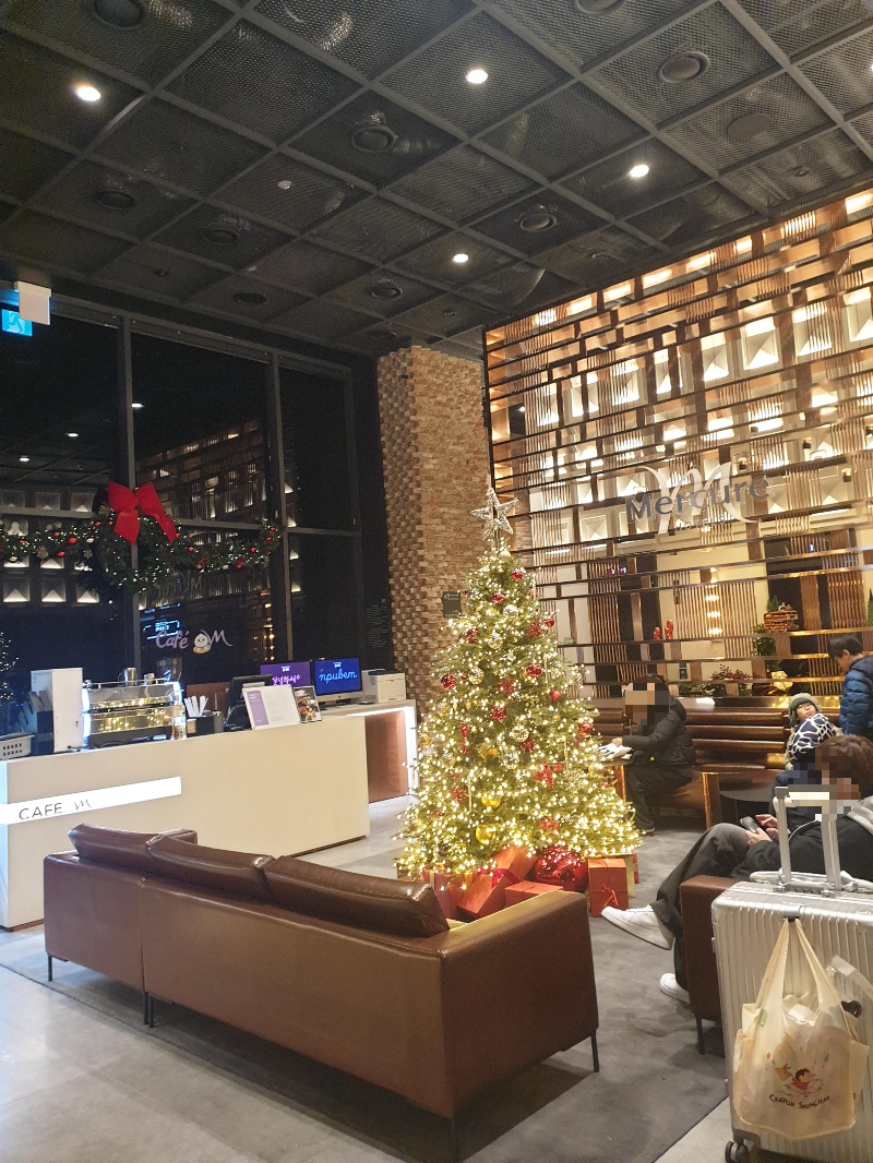 호텔 로비 소파 중앙에 크리스마스 트리가 장식되어 있다.