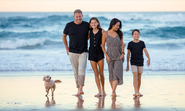 부모가 두 자녀와 강아지와 함께 해변을 걷는 장면