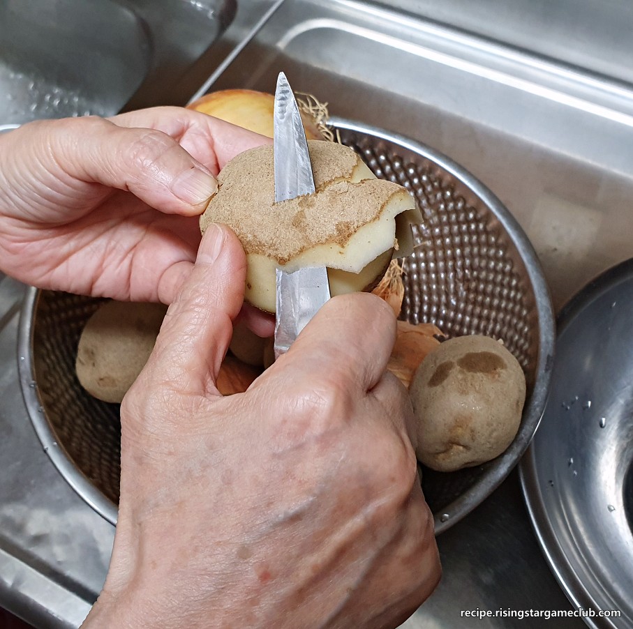 돼지고기 카레라이스에 들어갈 감자의 껍질을 깎는 사진