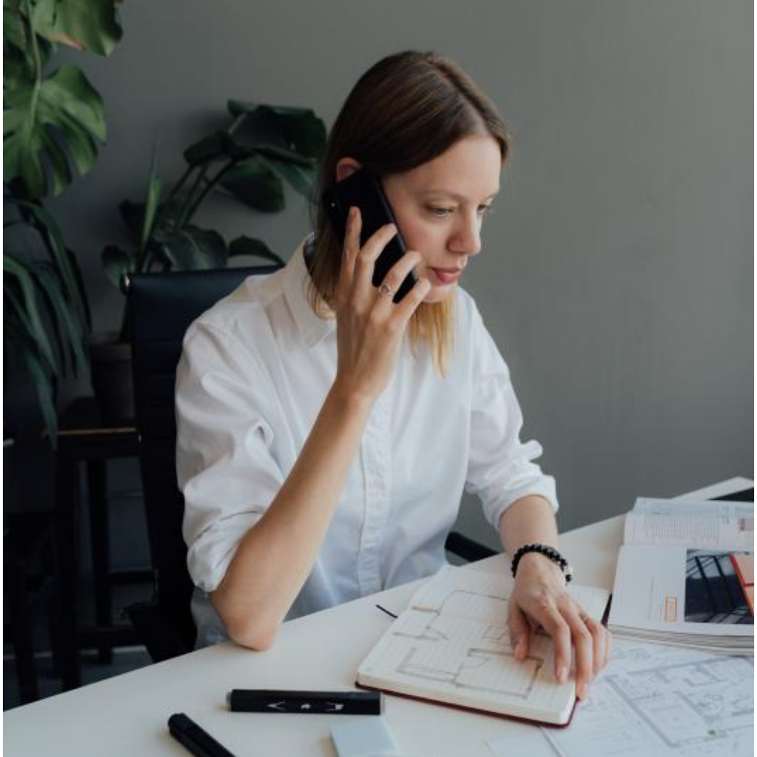 한 여성이 책상에 앉아 전화를 하고 있다.
