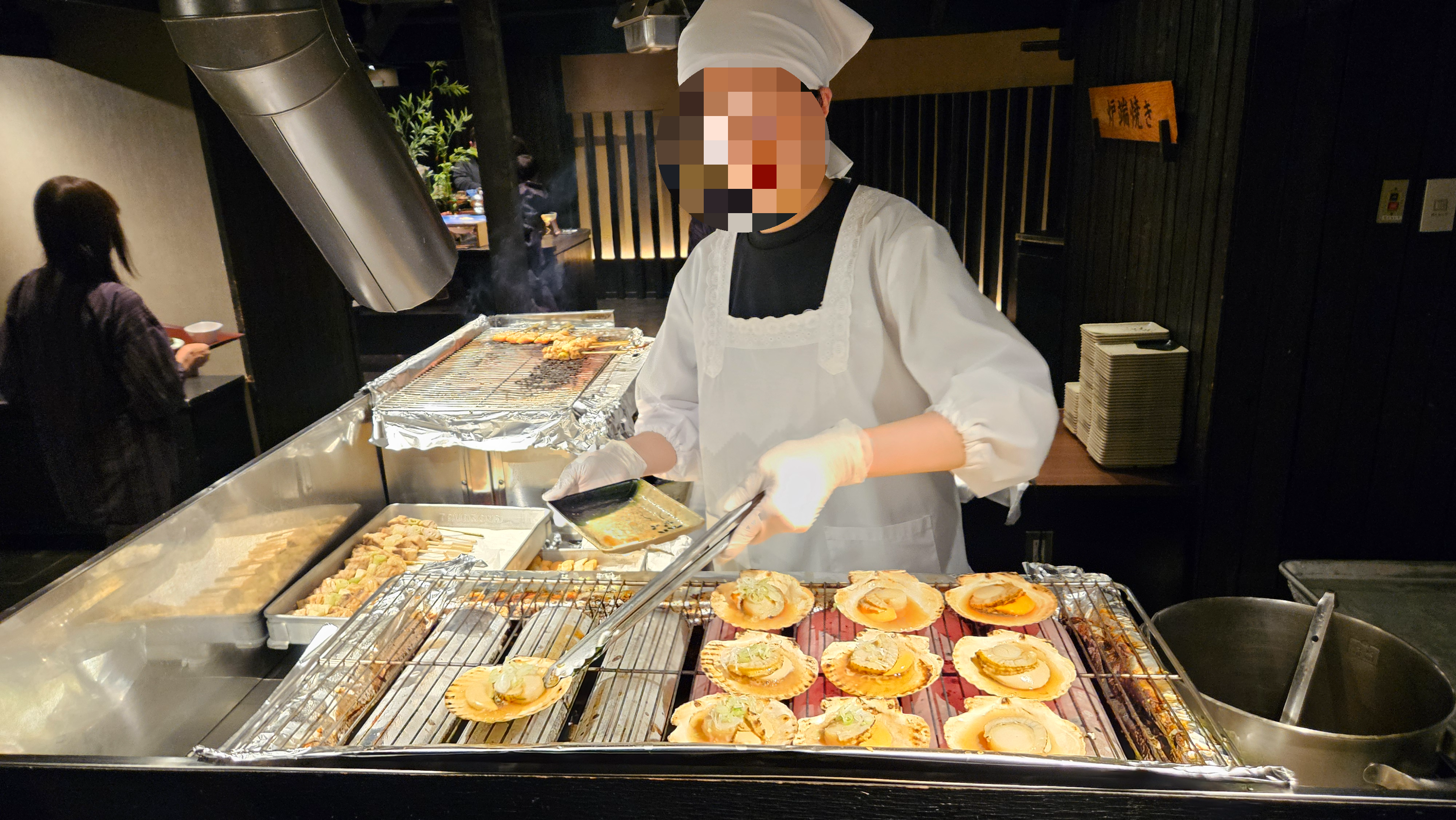 노레소레 식당의 라이브 키친 구역. 위생모와 조리복을 착용한 요리사들이 화로에서 가리비와 꼬치구이를 직접 굽고 있는 생동감 넘치는 모습.