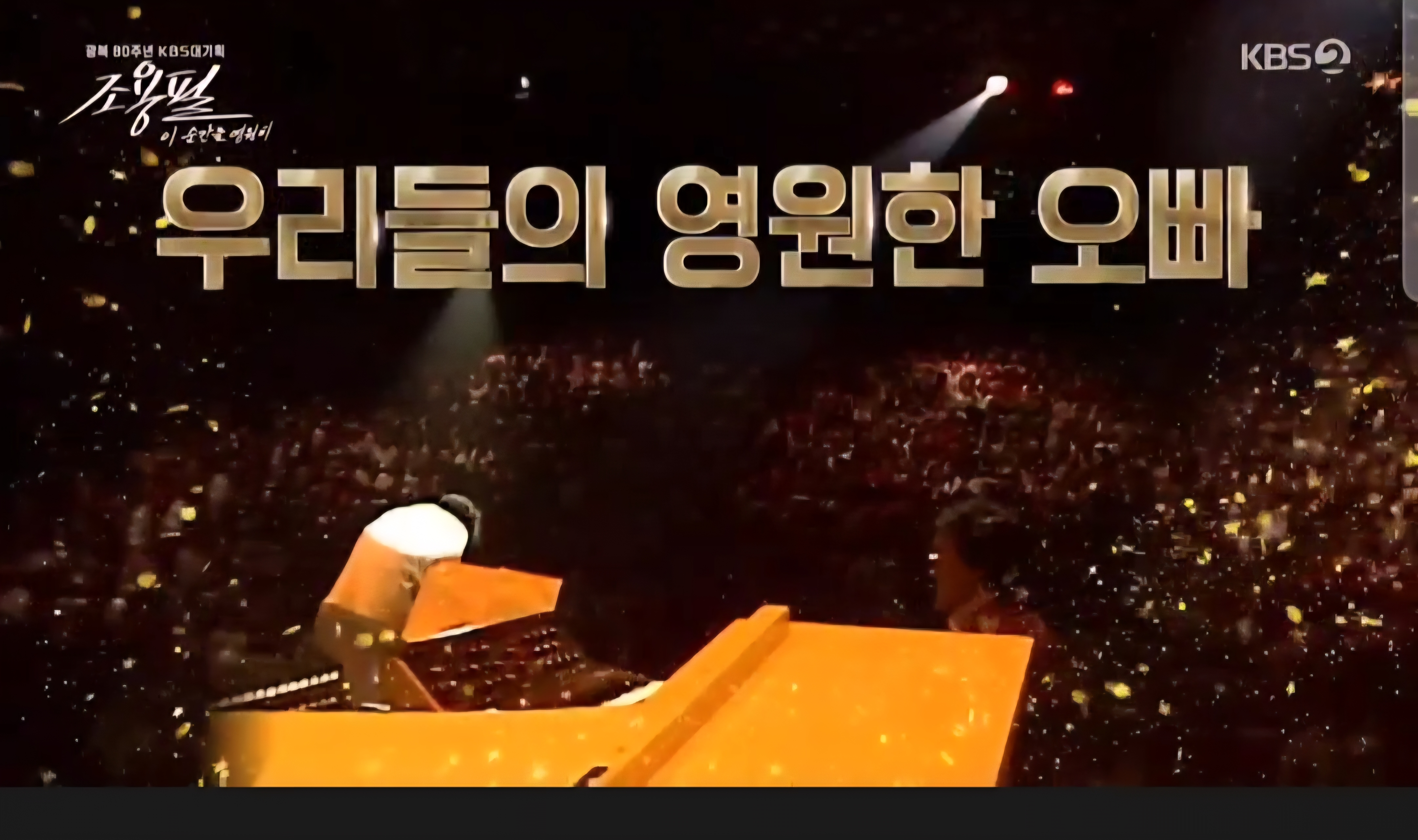 KBS 대기획 조용필 50주년 특집 ‘우리들의 영원한 오빠’ 타이틀 장면. 황금빛 무대 조명과 관객석의 환호가 어우러진 장면.