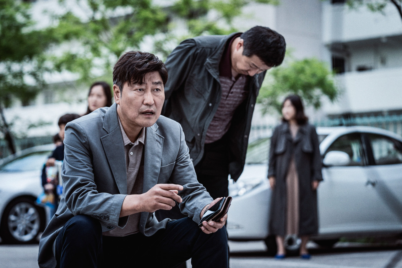 영화 속 송강호가 앉아있다.