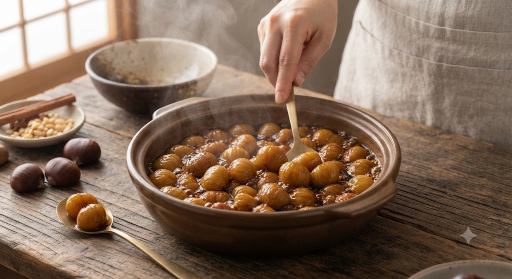 A candid shot capturing the process of making Korean-style candied chestnuts. A generous amount of chestnuts is simmering in a savory-sweet soy-based glaze inside a dark, earthenware pot, and warm steam is visibly rising. A person, wearing an apron, uses a gold ladle to scoop the chestnuts from the bubbling pot. Raw chestnuts, discarded shells, pine nuts, and cinnamon sticks are spread across the wooden table, illustrating the preparation steps.