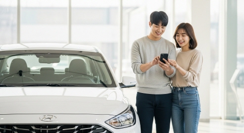 젊은 커플이 차량 옆에서 스마트폰으로 등록을 완료하고 기뻐하는 모습