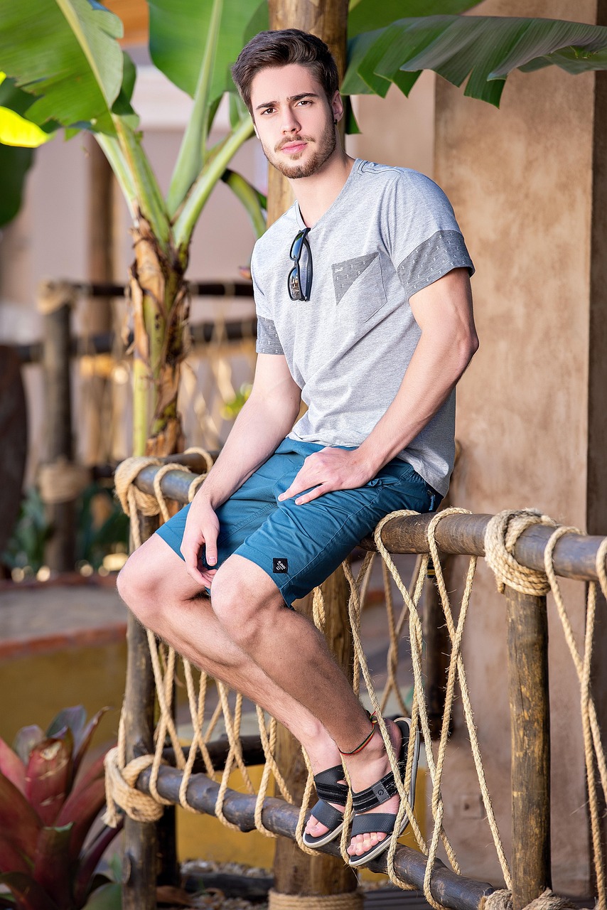 반팔,반바지에 슬리퍼를 신고 울타리에 앉아있는 남자