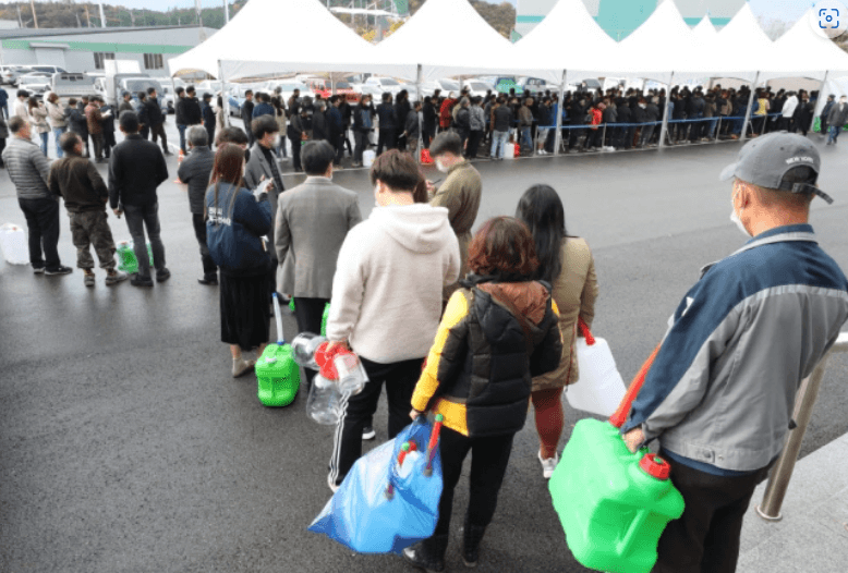 사람들이 빈 통를 들고 요소수를 받기위해 줄서있는 모습