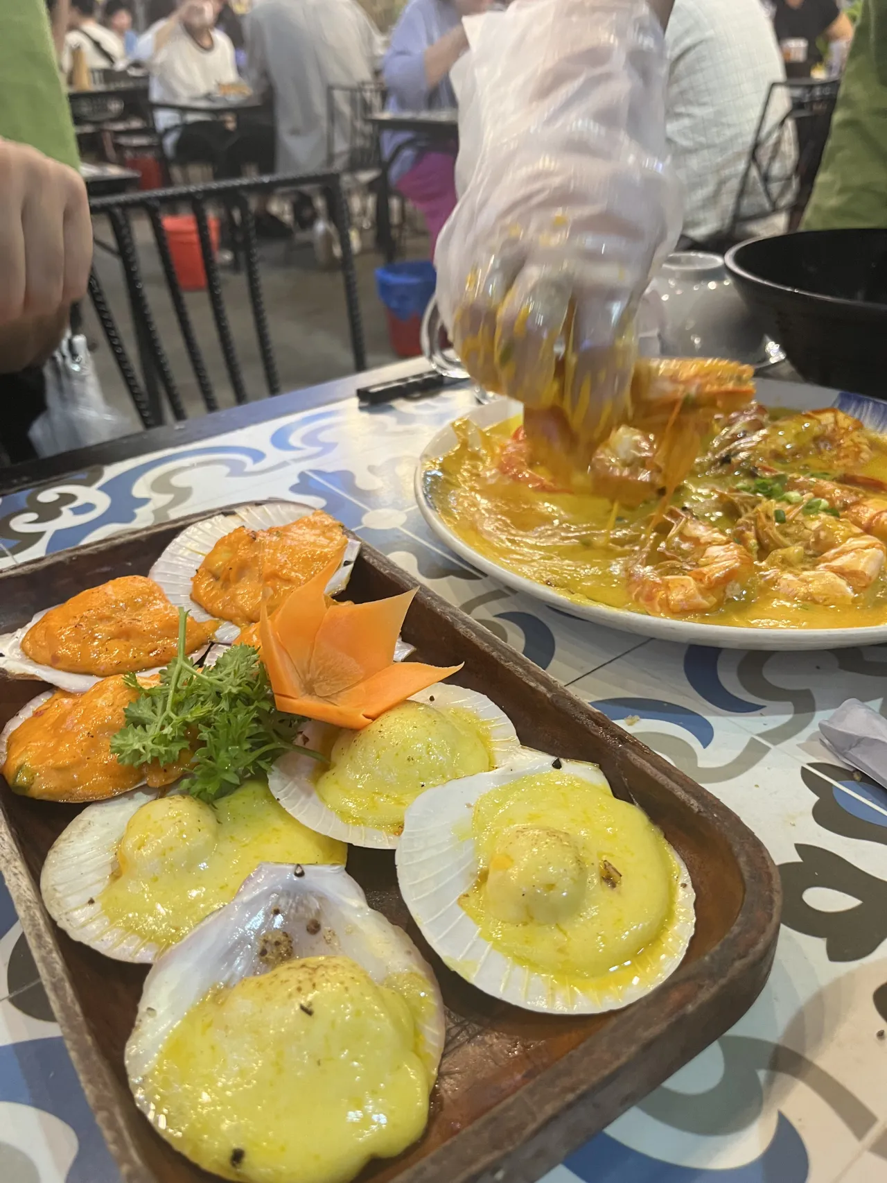 치즈가-뿌려진-가리비-옆에-토마토-소스-가리비-옆에-새우-요리가-담긴-접시-비닐장갑을-끼고-음식을 집는-손