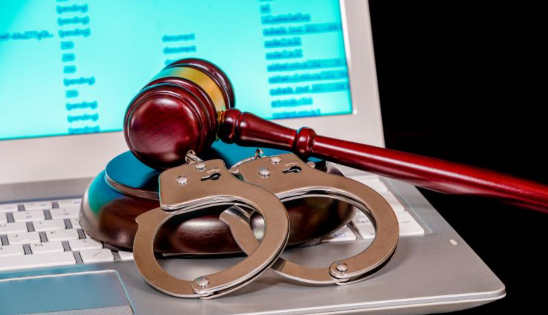 노트북 위에 수갑과 판사봉이 놓여있다.