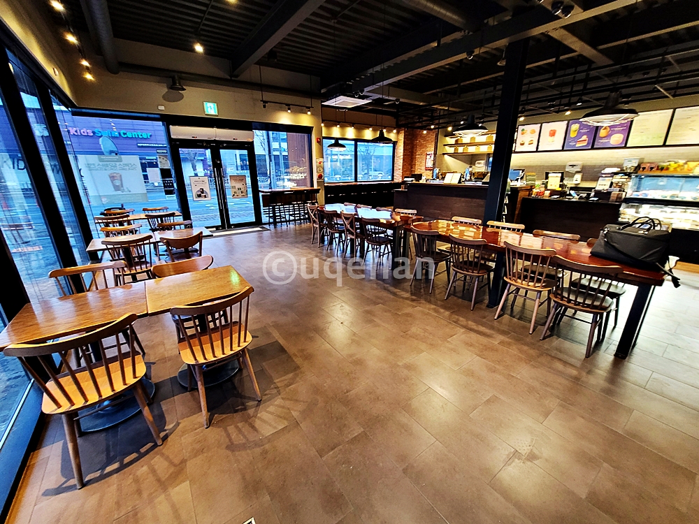 동두천 DT 스타벅스 1층의 전경이다. 테이블과 의자가 넓게 배치되어 있고, 벽쪽으로 카운터 및 음료제조 시설이 갖춰져있다.