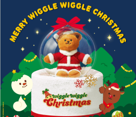 파란색 배경 앞 초록색 나문 일러스트들 앞 생크림 케이크 위 투명볼 안 곰돌이 인형이 든 케이크