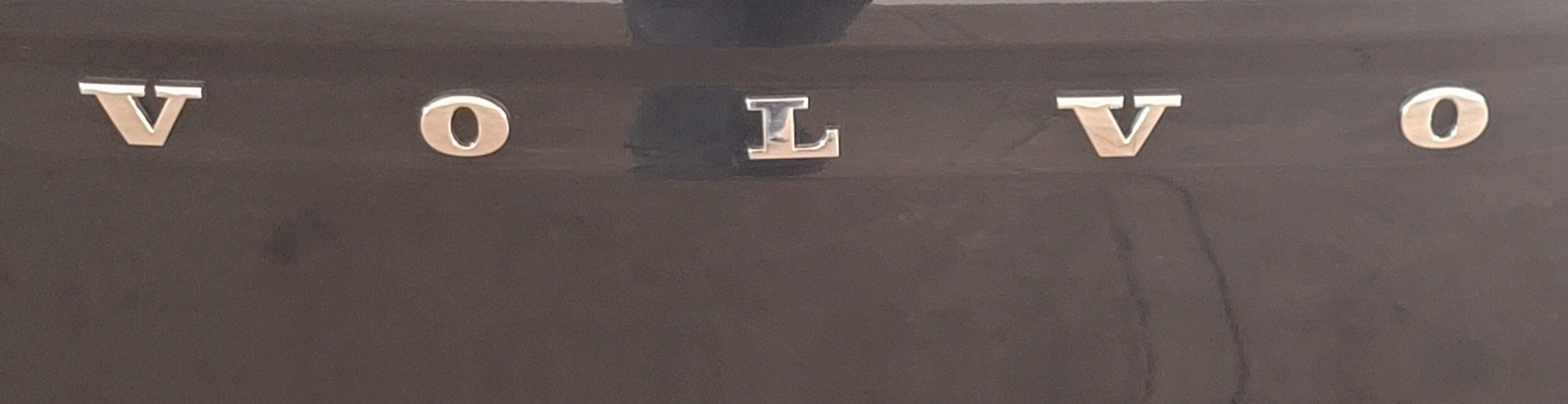 삐뚤어진 차량 후면 볼보 레터 엠블렘 모습이다. L이 기울어져 있다.