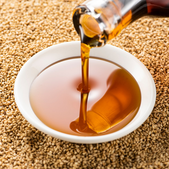 하얀그릇에 붓고있는 참기름과 그 아래 깨