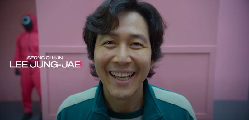 분홍색 실내를 배경으로 환하게 웃고 프로필 사진을 찍고 있는 성기훈 역의 배우 이정재