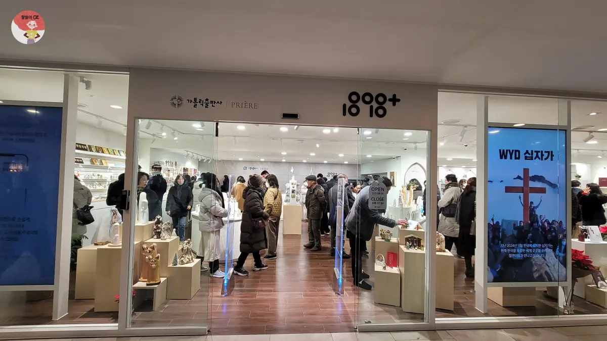 명동-명동문고-가톨릭출판사-외관-하얀바탕에-쓰인-상호명과 전면-유리문-사이로-꽉찬-사람들이-보임