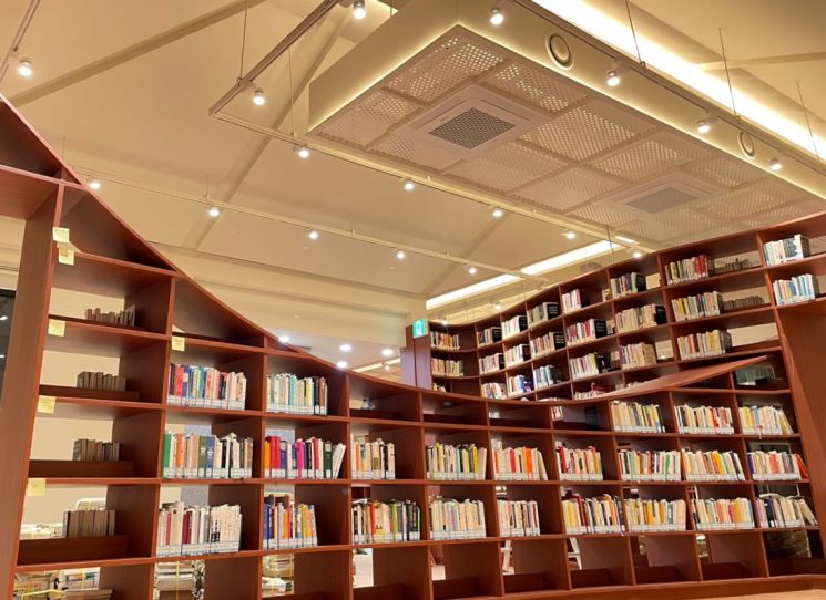 마라톤 트랙을 형상화한 곡선형 책장과 따뜻한 조명이 있는 손기정문화도서관 내부