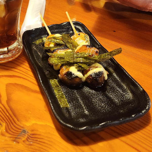 떡꼬치 구이 위에 치즈와 김이 뿌려져 있다.