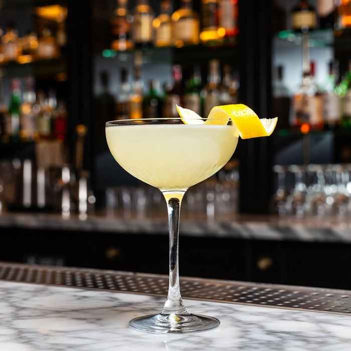 레몬 트위스트가 곁들여진 우아하고 맑은 빛깔의 20세기 칵테일 완성 사진