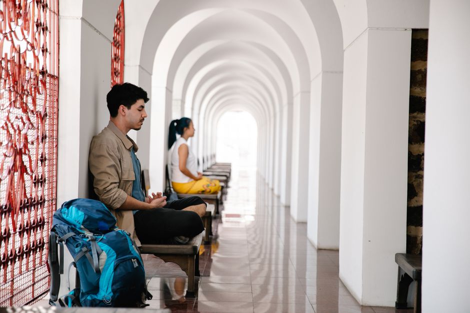 Two travelers meditate peacefully in an arched corridor, reflecting serenity and tranquility.