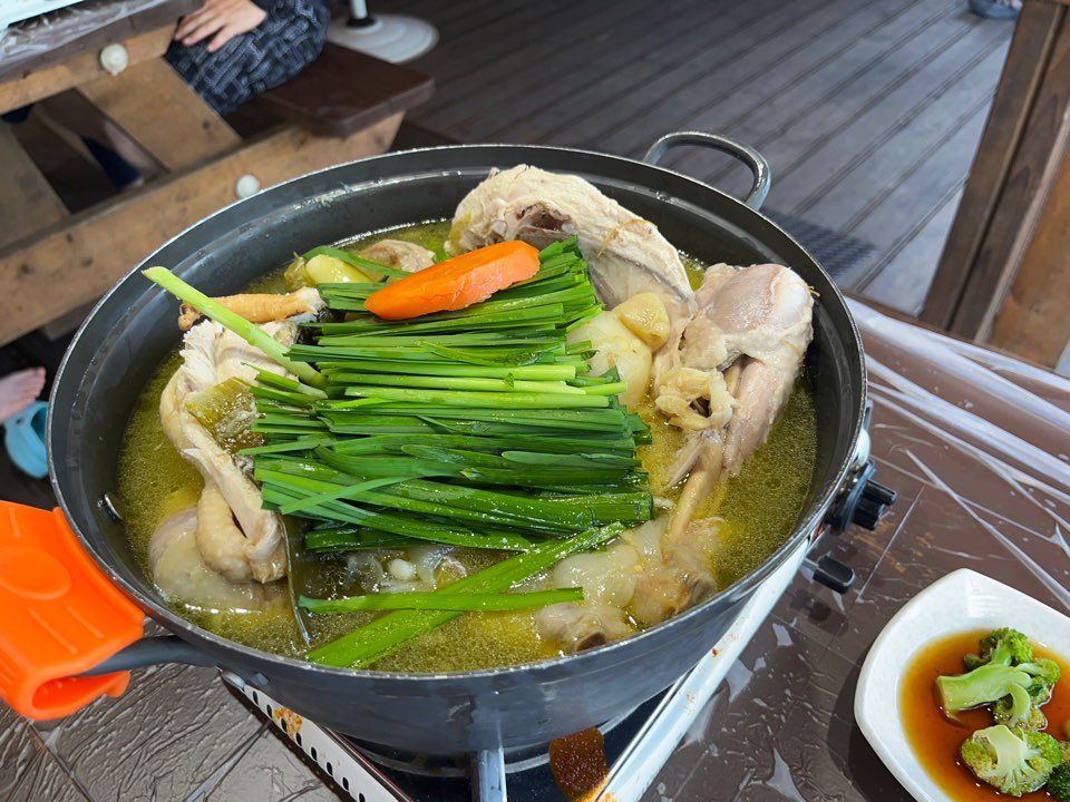 부추가 올려진 토종닭 백숙메뉴이며 닭의 크기는 냄비한가득 차있음