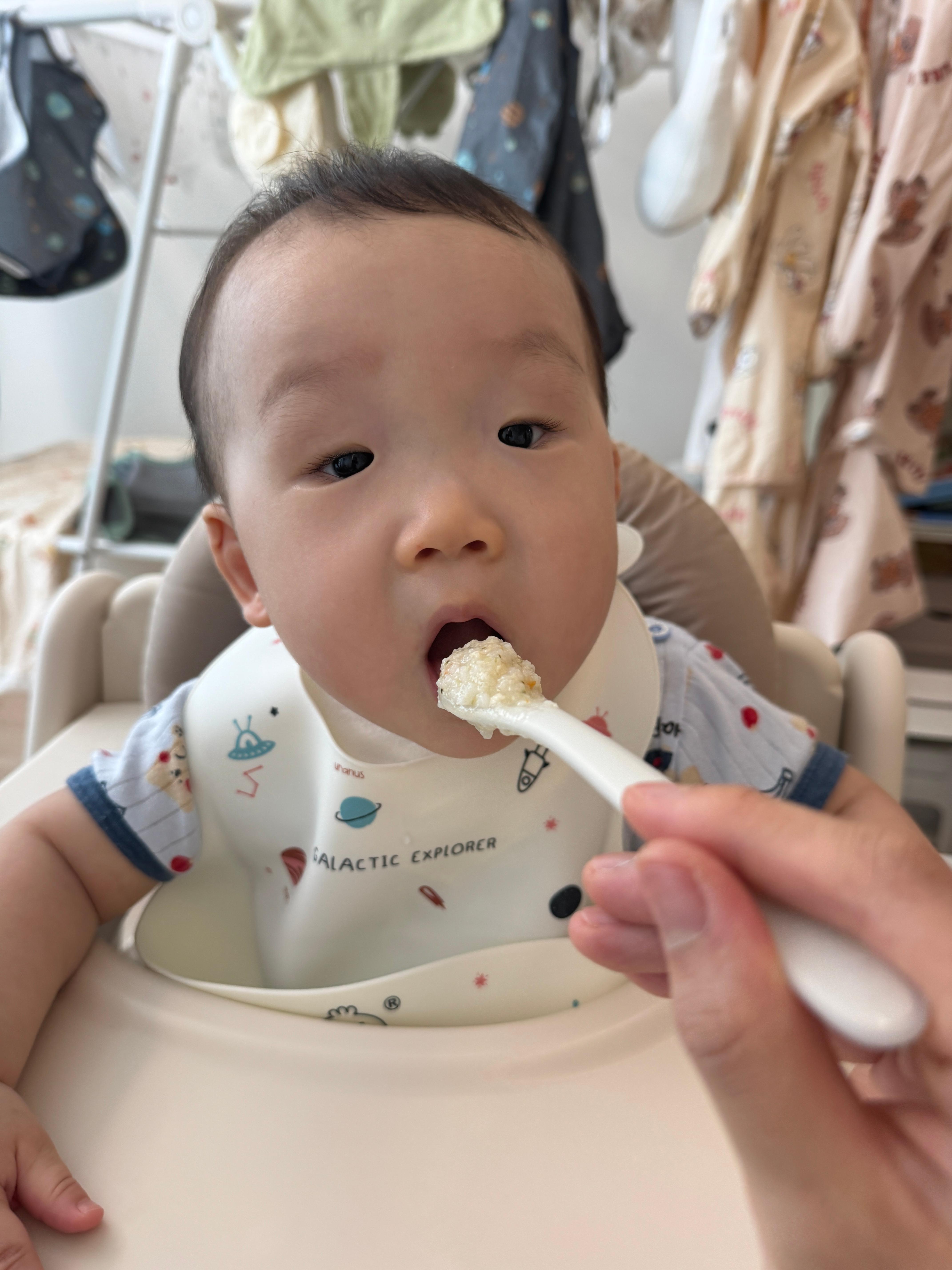 닭고기당근브로콜리죽을 먹으려고 입을 벌리는 아기