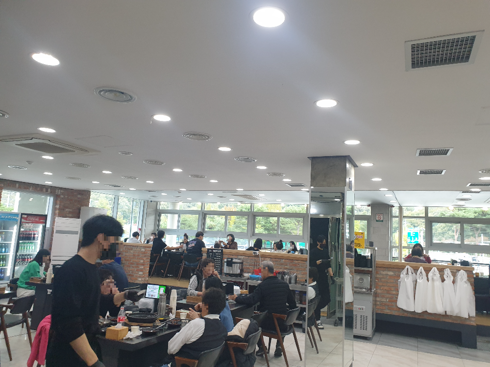 2층 넓은 홀. 홀은 단차를 두어 둘로 나누어져 있다. 홀에는 손님이 가득하고 직원들은 음식을 나누느라 바쁘다.