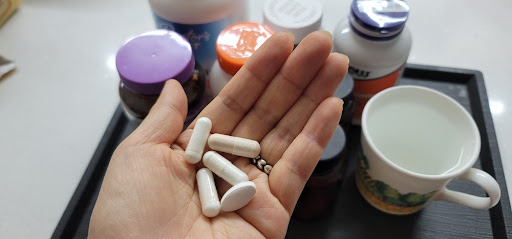 손 위에 여러 개의 알약과 캡슐이 놓인 모습