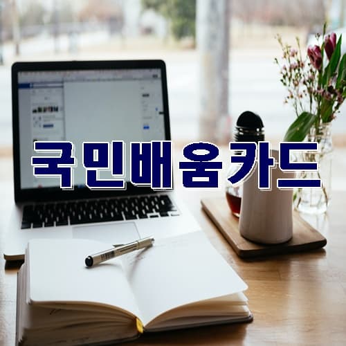 테이블위에 책이펼쳐저있고 노트북과 버그컵,꽃병이 놓여져있고 가운데 국민배움카드 문구가 쓰여진 이미지