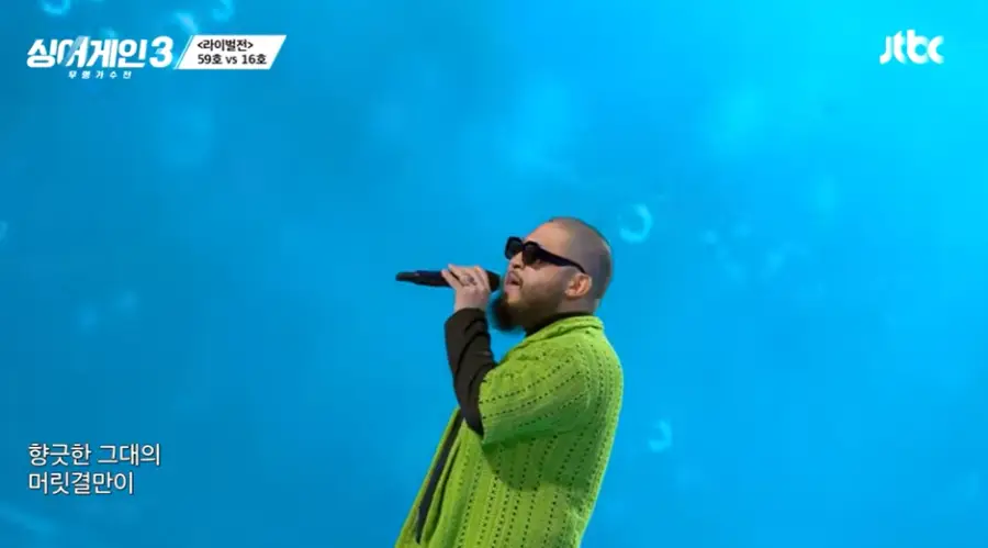 싱어게인3-
파란배경 연두색 스웨터 안 검은 폴로티를 입고 검은선글라스에 검은 마이크를 입에대고 노래하는 16의 왼쪽 옆모습