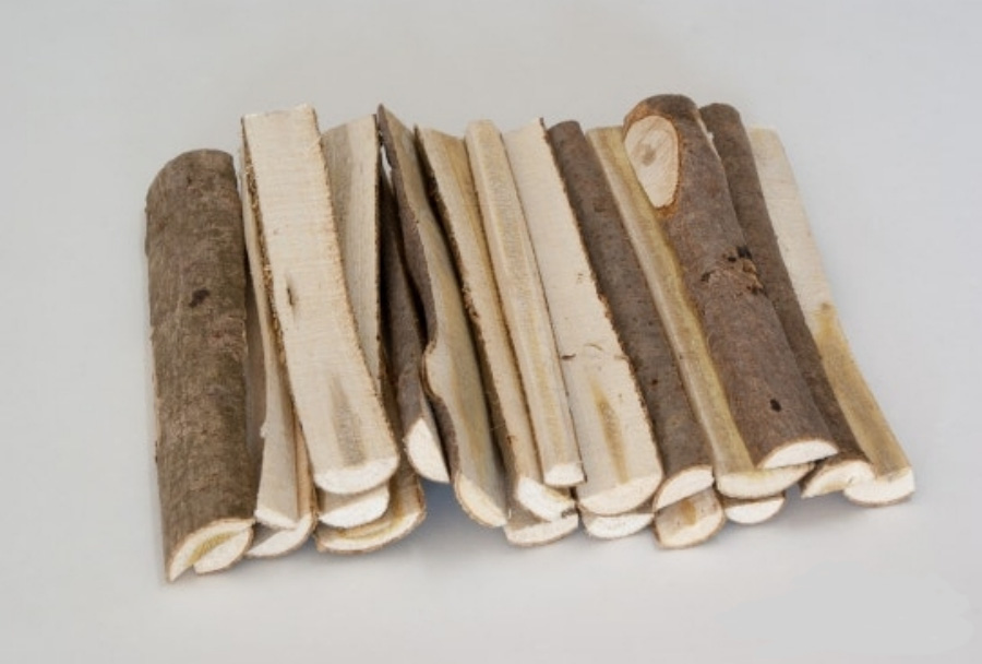 야생에서 채취를 한 옻나무를 깨끗하게 세척하고 건조시킨 것을 편으로 쪼개 놓은 것을 흰색 바닥 위에 수북하게 놓아두고 찍은 사진