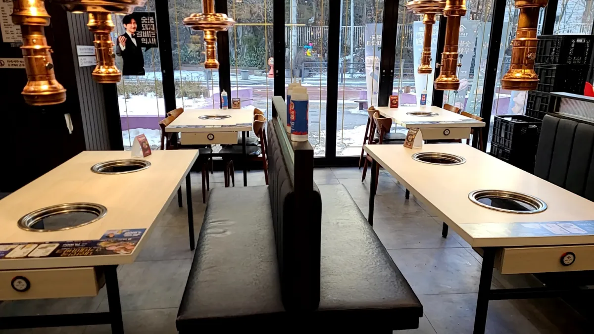 명륜진사갈비-실내-흰색4개테이블--테이블위에는-반짝거리는연기흡입기가-길게메달려있다