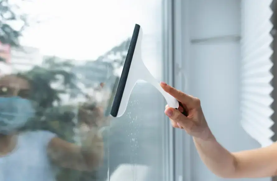 창문 청소 도구로 유리창을 닦고 있는 모습. 창문 청소 노하우를 보여주는 장면으로, 맑고 깨끗한 유리창 관리의 중요성을 강조하는 이미지