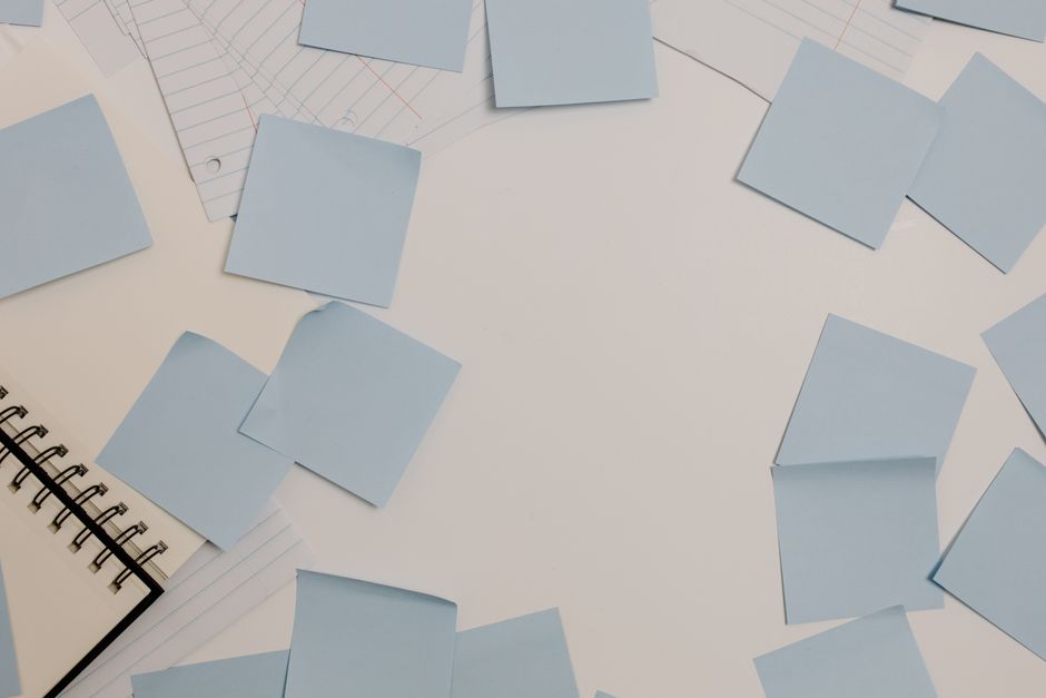 Top view of a desk with blue sticky notes, a spiral notepad, and lined papers.