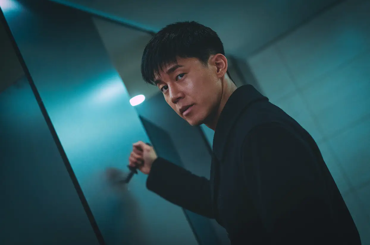 범죄도시-화장실안 검은옷을 입고 오른손에 칼을 들고 화장실 문에 대고 살벌한 눈으로 바라보는 김무열