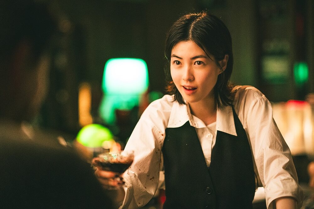 영화 더 킬러스 스틸컷 &ndash; 주인공 여배우가 잔을 건네며 사건의 서막을 여는 장면