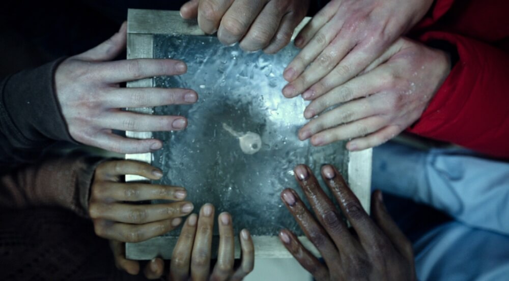 영화 이스케이프 룸 스틸컷 – 참가자들이 얼음 위의 열쇠를 손에 얹고 있는 상징적인 장면