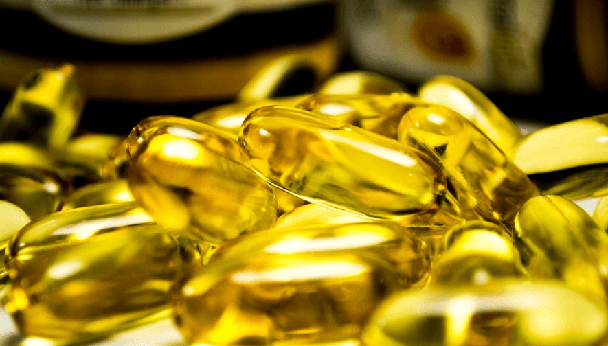 중성 지방 낮추는 방법으로 도움이 되는 오메가 3 캡슐 여러 개가 놓여 있다
