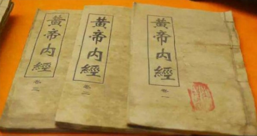 한의학의 옛 고서인 황제내경 권 1, 권, 2, 권3을 주황색 바닥 위에 서로 포개서 놓아두고 찍은 사진