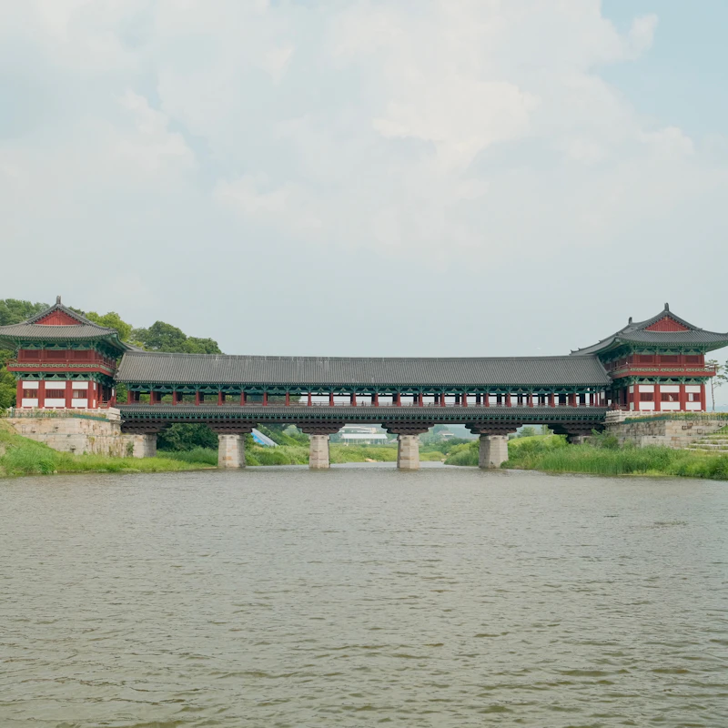 경주 월정교 전경, 강물 위에 세워진 전통 목조 교각과 붉은 단청 누각이 좌우 대칭으로 펼쳐진 낮 풍경