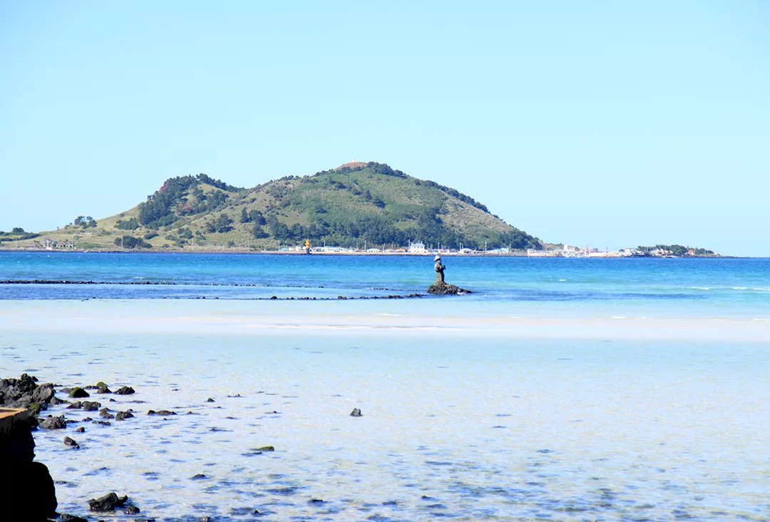 제주 올레길 14코스 해안 구간의 하이라이트인 금능 및 협재 해수욕장에서 바라본 에메랄드빛 바다와 건너편의 비양도 전경 사진.
