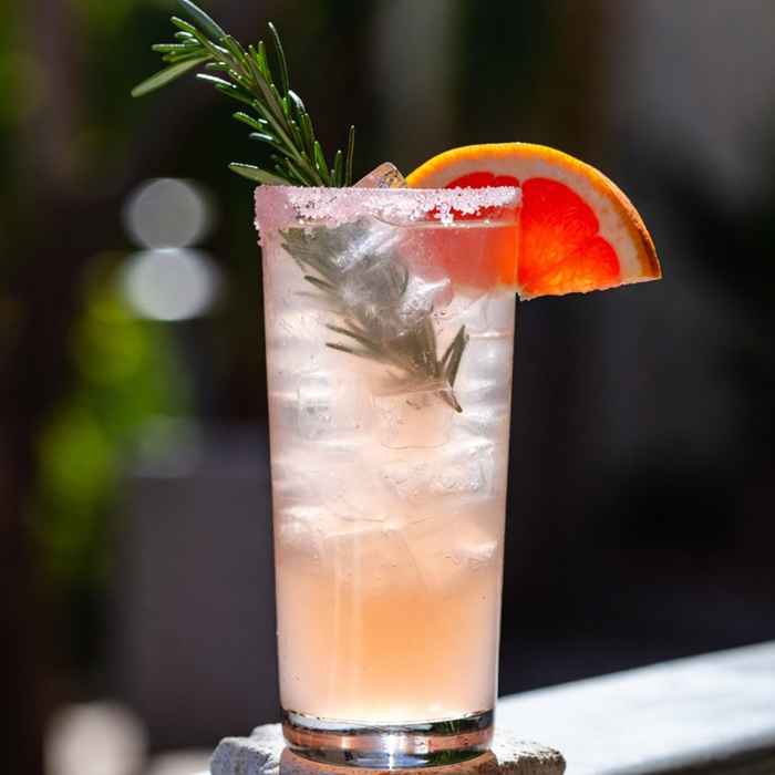 자몽 웨지와 로즈마리로 장식된 시원한 핑크빛 메스칼 팔로마 완성 사진