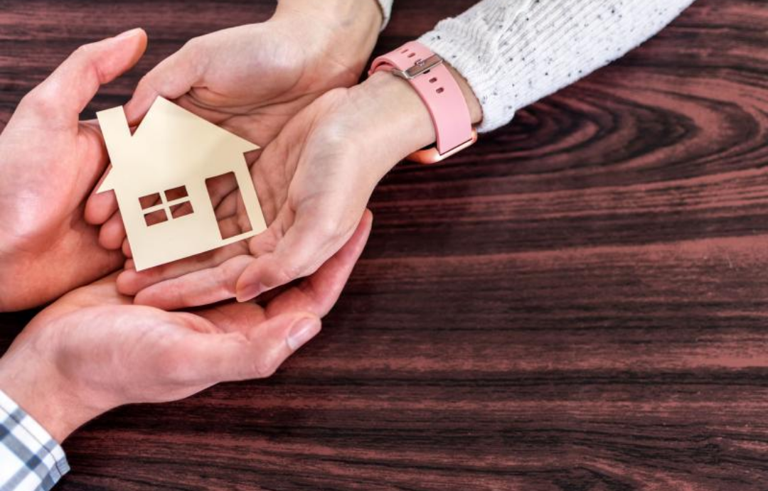 남녀가 두손을 맞잡고 집 모형을 들고 있다.