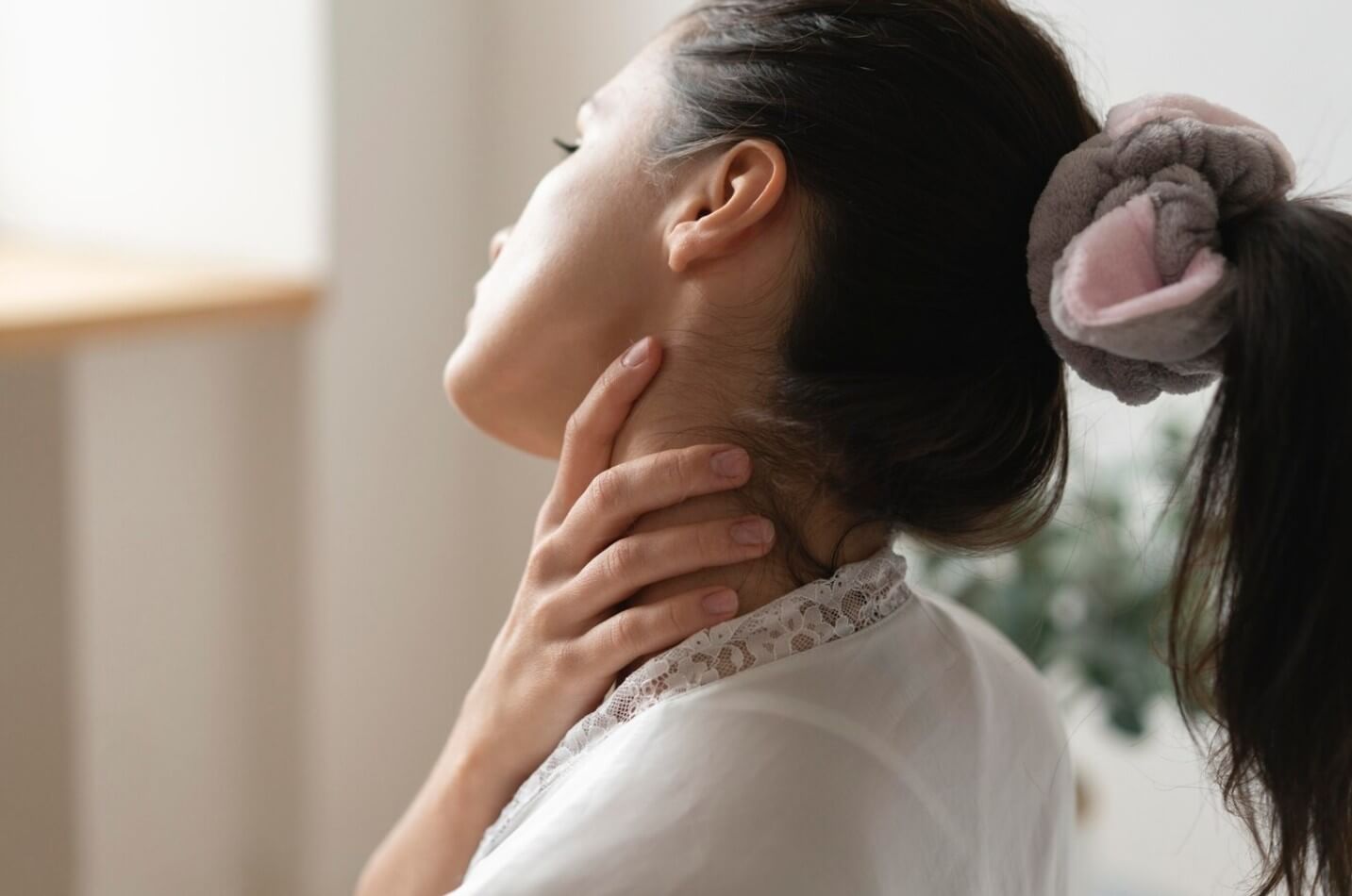 목을 만지고 있는 여성