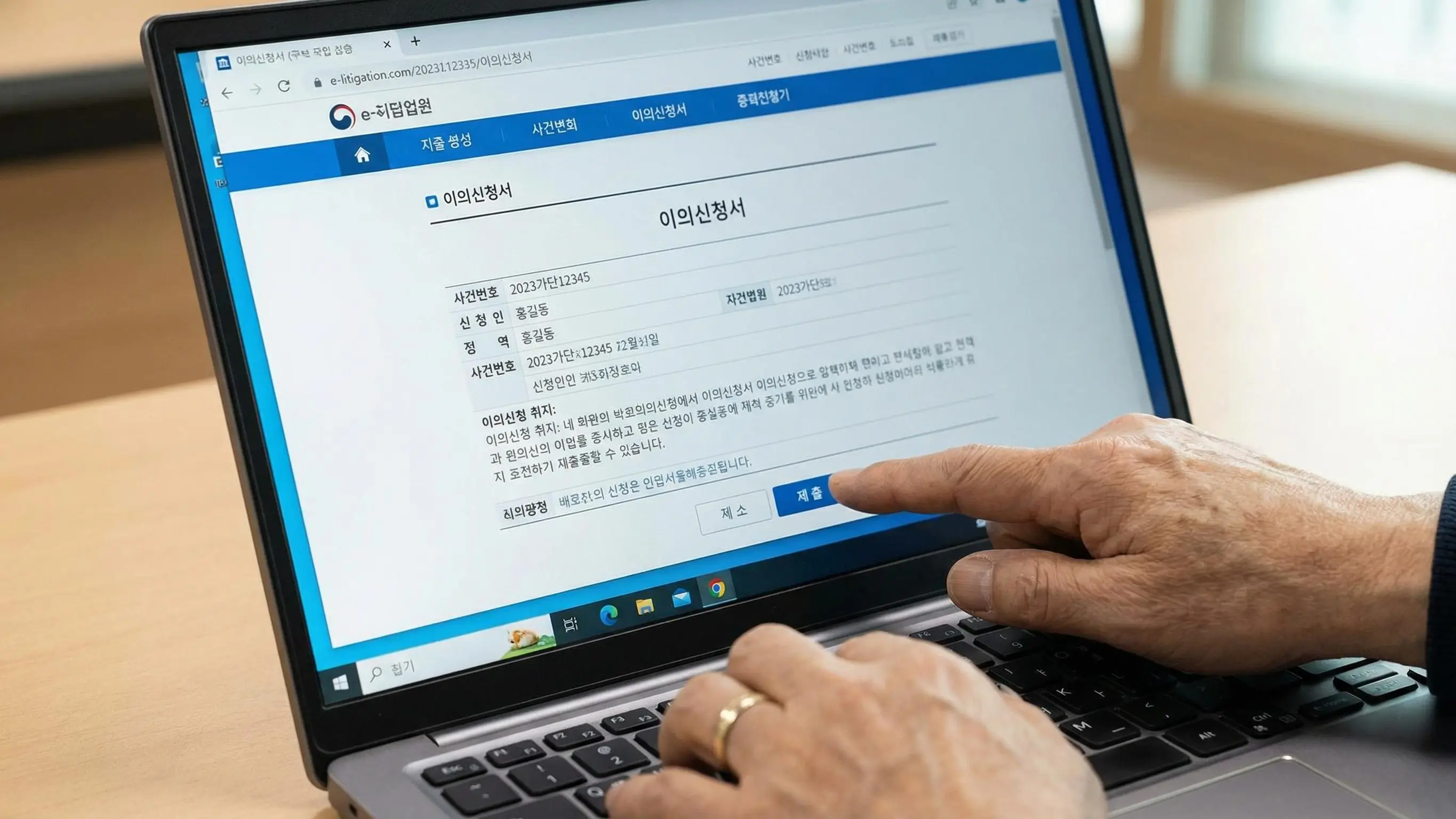 전자소송 사이트 화면을 보며 이의신청서를 작성하고 제출 버튼을 누르는 손의 클로즈업